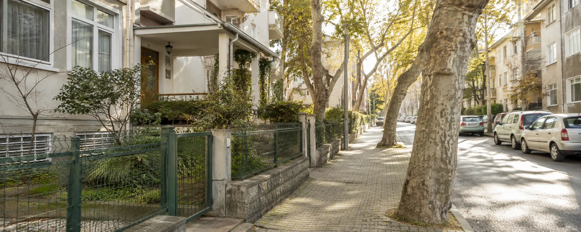 İstanbul’da ağaçlıklı sakin bir mahalle sokağı ve bahçe katlı bina girişi